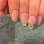 Close-up of cute frog nails with colorful designs and artistic nail art