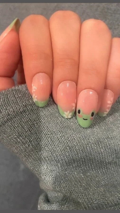 Close-up of cute frog nails with colorful designs and artistic nail art