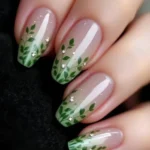 Acrylic green nails with gold leaf designs and sage ombre finish for stylish manicures.
