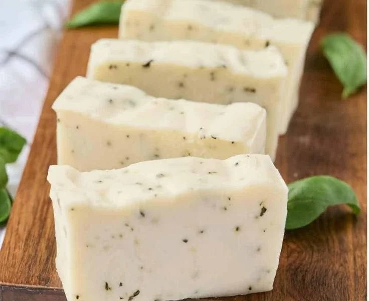 Homemade basil soap with fresh herbs displayed on a rustic background