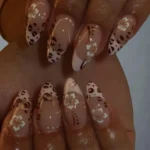 Leopard print press on nails with white floral art, brown spots, and gold accents.