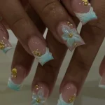 Light blue and gold flower nails with French tips on acrylic design for black skin