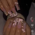 White flower nails with rose gold and brown design featuring gems.