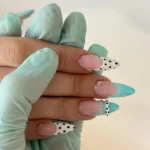 Turquoise dot French tip design on almond-shaped dotted nails.