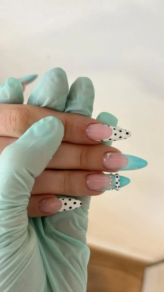 Turquoise dot French tip design on almond-shaped dotted nails.