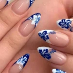 Blue and white hibiscus nail art design featuring trendy French tips