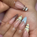 Beautiful yellow almond nails design with brown and blue for a summery vibe.