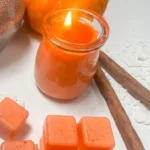 Homemade pumpkin spice candle with fall decorations for a cozy atmosphere.