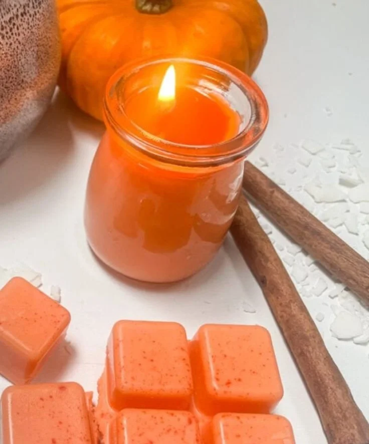 Homemade pumpkin spice candle with fall decorations for a cozy atmosphere.