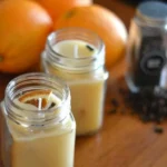 Homemade orange and clove beeswax candles on a wooden table.