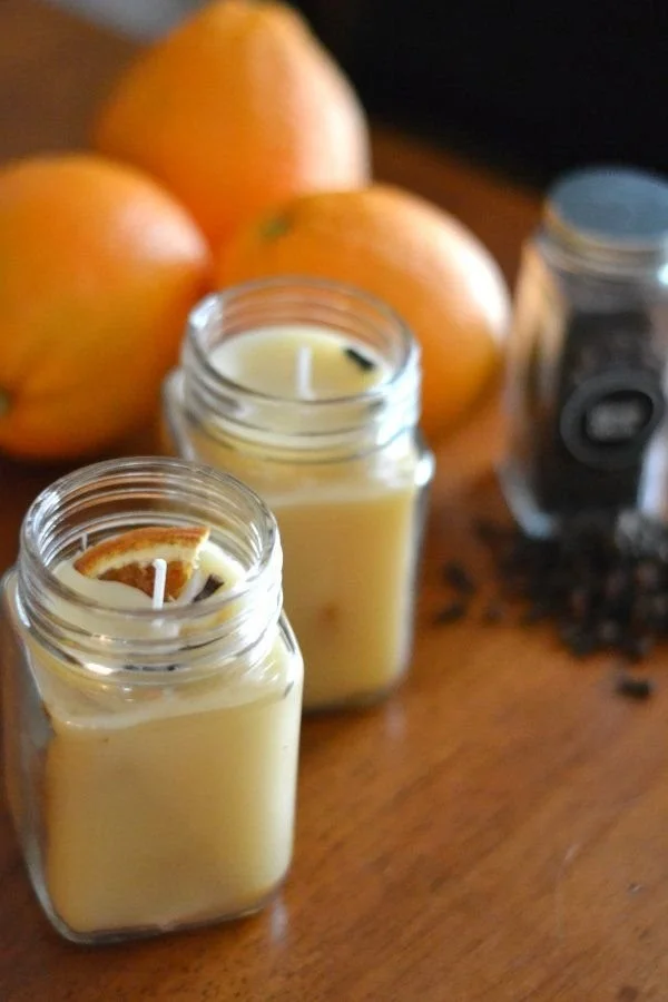 Homemade orange and clove beeswax candles on a wooden table.