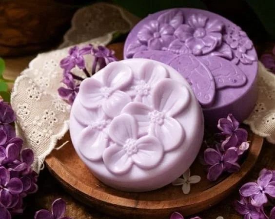 Homemade lilac soap bars displayed with lavender flowers