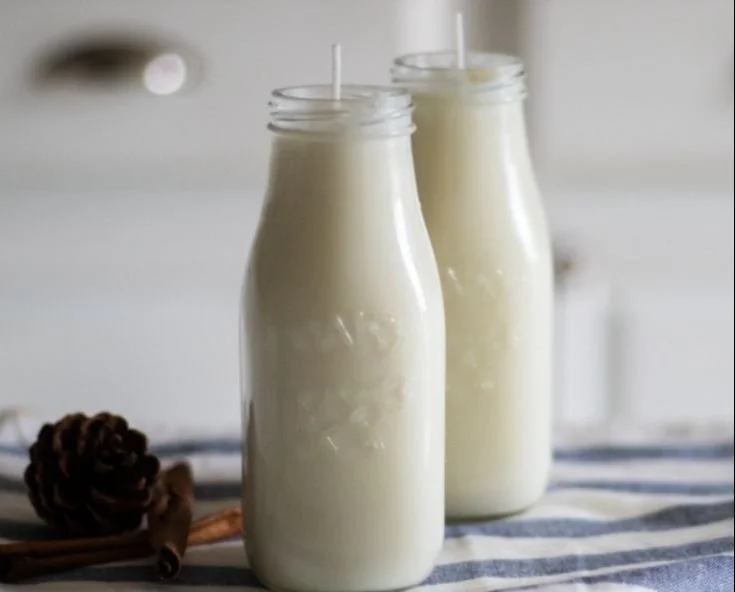 DIY milk jug candles with colorful wax and wicks in a cozy setting.