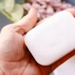 Handmade coconut oil soap bars on a wooden surface with natural ingredients.