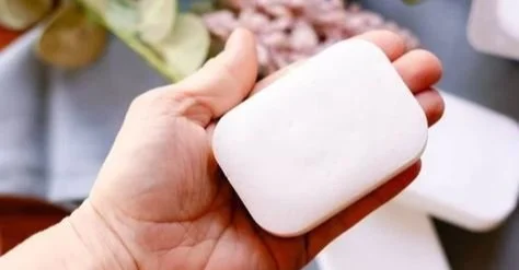 Handmade coconut oil soap bars on a wooden surface with natural ingredients.