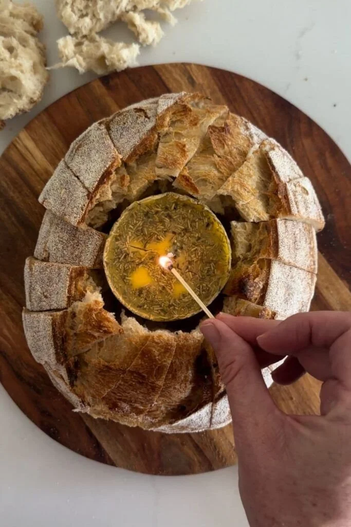 Homemade butter candle beside fresh sourdough bread on a wooden table.