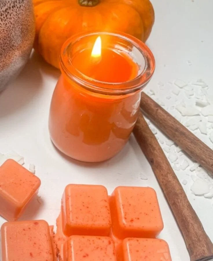 Homemade pumpkin spice candle glowing warmly in an autumn setting