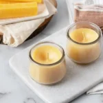 Homemade scented beeswax candles with essential oils on a table.