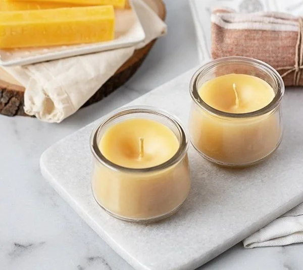 Homemade scented beeswax candles with essential oils on a table.