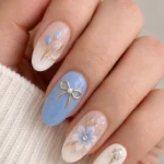 Sky blue nails featuring delicate floral bow designs for a stylish manicure.